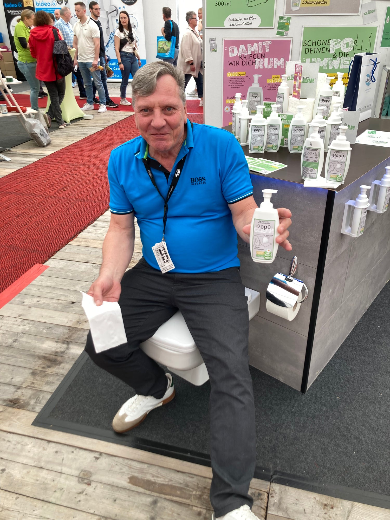 Der Geschäftsführer von PopoClean auf einer Messe mit einer Flasche Popo Schaum in der Hand